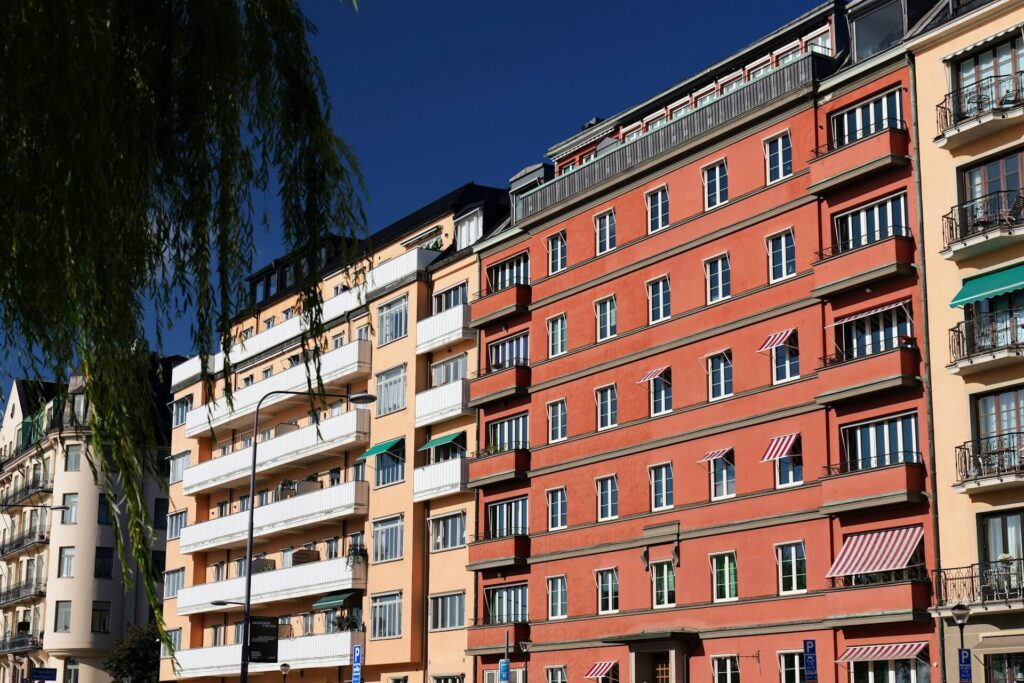 Stor lägenhetsbyggnad i röda och gula färger under en solig dag