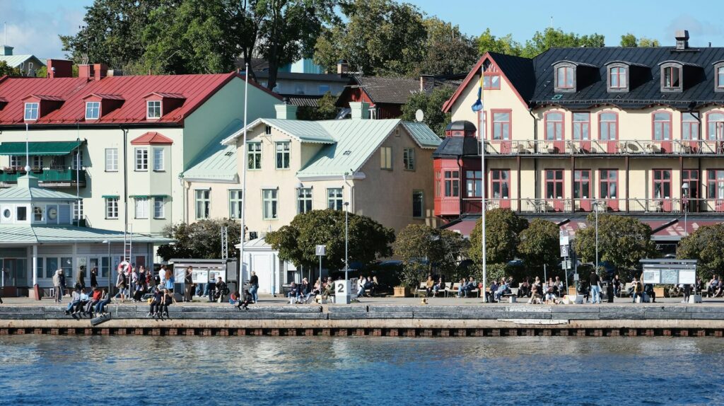 Flera hus i olika färger nära en flod med mycket människor i en solig dag