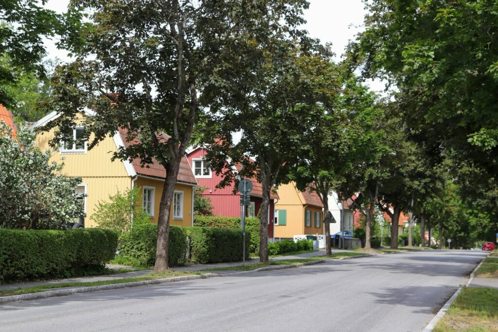 lång och tom gata med många träd och radhus vid sidan under dagen